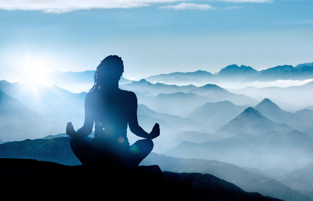 picture of a yogi meditating facing the mountains.